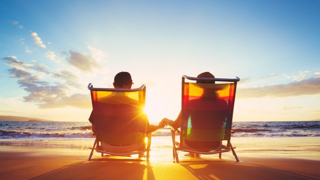 Retired couple sat in deckchairs on the beach